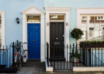 Две съседни жилища с черна и синя входни врати и ограда от ковано желязо